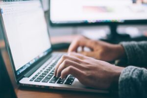 An image of someone's hands typing on a laptop with a word document open.