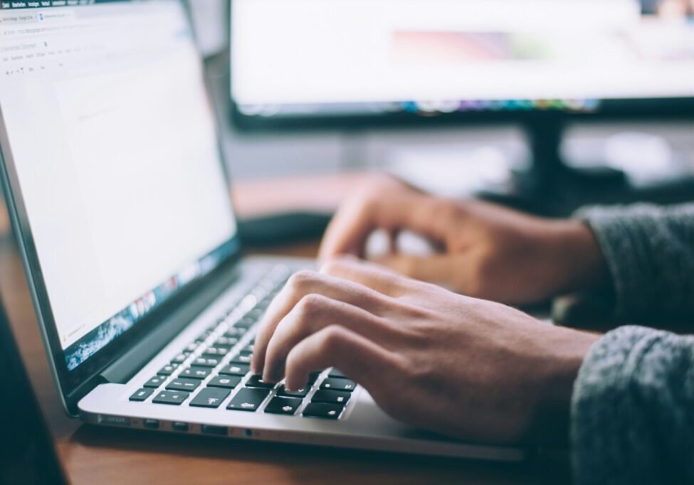 An image of someone's hands typing on a laptop with a word document open.